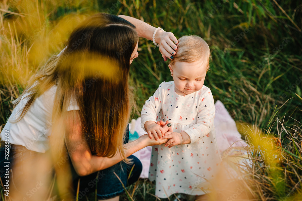 Naklejka premium Portrait of a daughter toddler and mother on nature on summer day vacation. Mom and girl playing in the park at the sunset time. Concept of friendly family. Close Up.