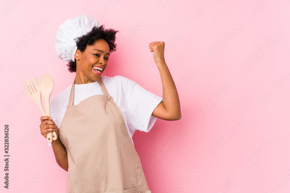 Young african american cook woman raising fist after a victory, winner concept. Young african american cook woman raising fist after a victory, winner concept.