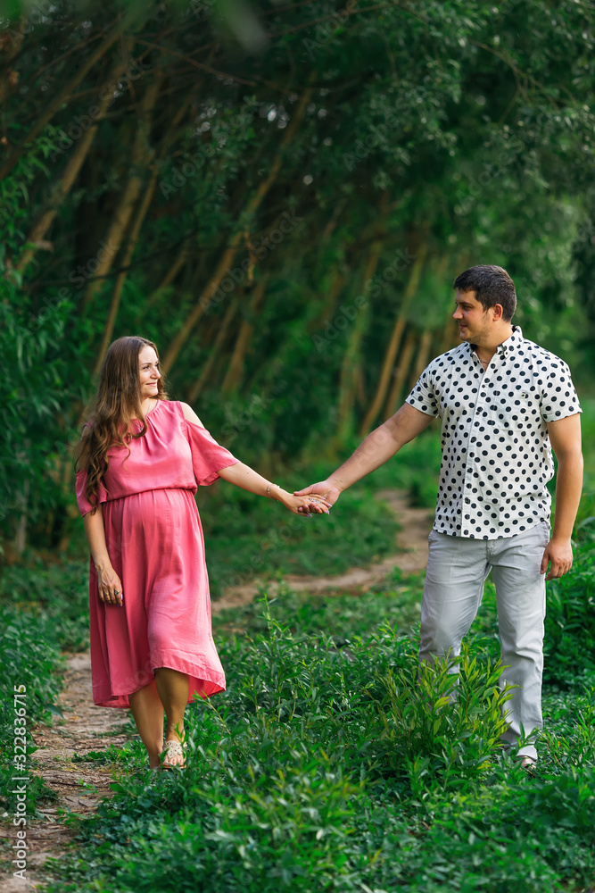 Fototapeta premium husband hugging pregnant wife in pink dress. expectant parents w