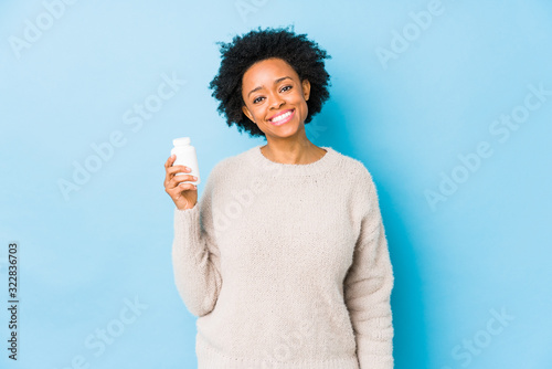 Middle age african american woman holding a vitamin bottle happy, smiling and cheerful. photo