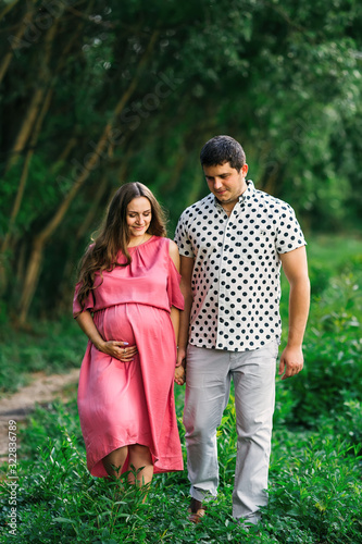 Future parents walking in the park. pregnant woman in pink dress