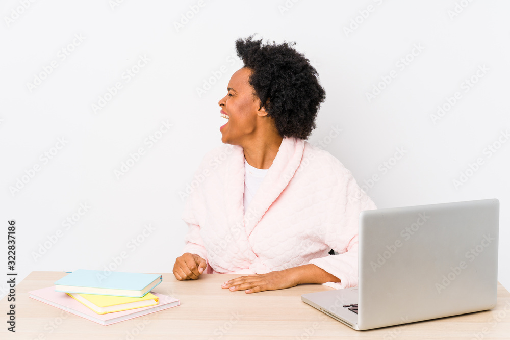 Middle aged african american woman working at home isolated shouting towards a copy space