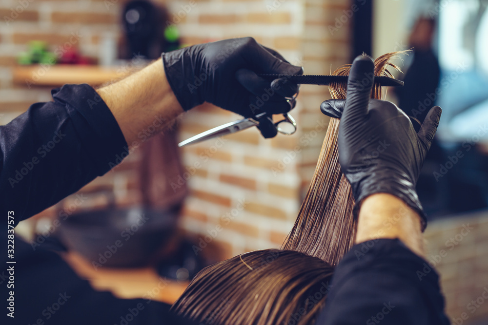 Naklejka premium Close-up of man haircut, master does the hair styling in barber shop.