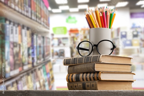 Stack of vintage books, glasses and colorful pencils on the desk