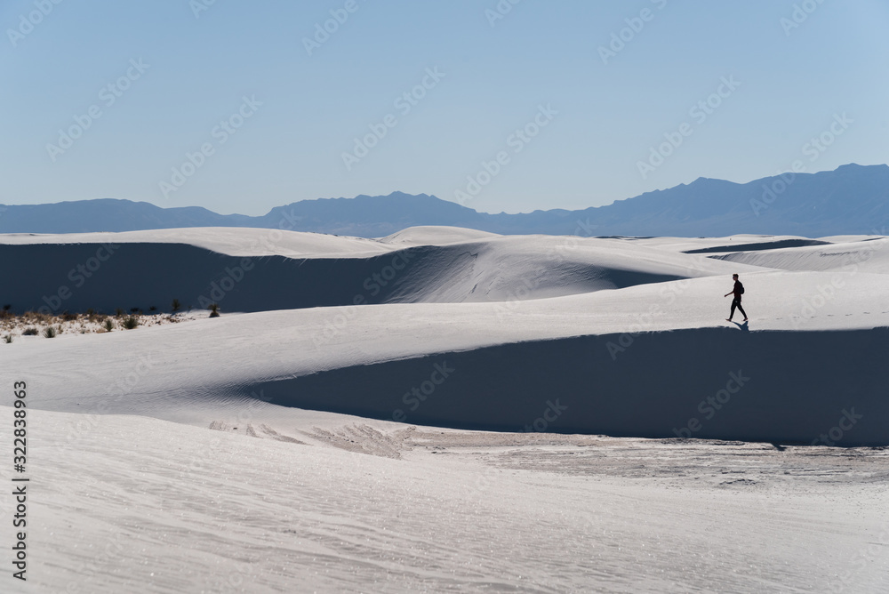 A man walking in the distance at White Sands National Park in Alamogordo, New Mexico. A man walking in the distance at White Sands National Park in Alamogordo, New Mexico.