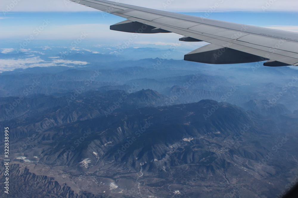 wing of an airplane flying above the clouds wing of an airplane flying above the clouds