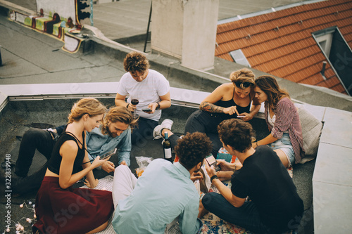 High angle view of distracted friends using mobile phones while partying on rooftop photo