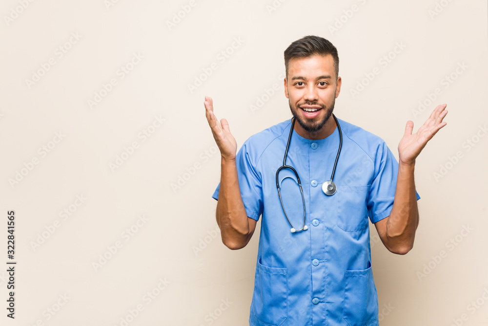 Young south-asian nurse man receiving a pleasant surprise, excited and raising hands. Young south-asian nurse man receiving a pleasant surprise, excited and raising hands.