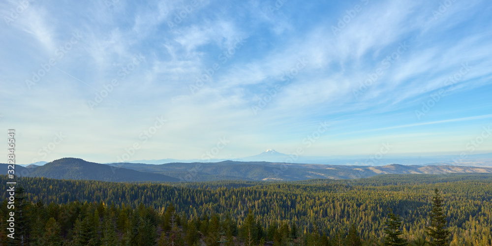 Evening blue sky view over the wooded mountains in Oregon. Mountains Adams and Rainier in the background.