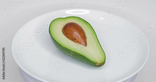 Rotating Avocado on a Plate. real time. Shot on Canon 1DX mark2 4K camera photo