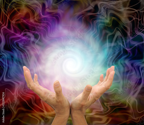 Creating a Healing Rainbow Energy Vortex from White Light - female open hands with a spiralling white energy formation above inside a multicoloured gaseous energy field 