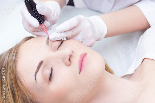 Close-up of a young woman undergoing permanent eyebrow makeup in a beauty salon