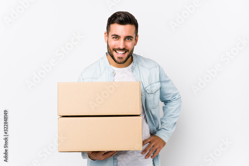 Young caucasian man moving to a new home isolated laughing and having fun.