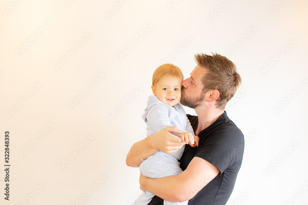 Young man kissing his baby and smiling in arms Young man kissing his baby and smiling in arms