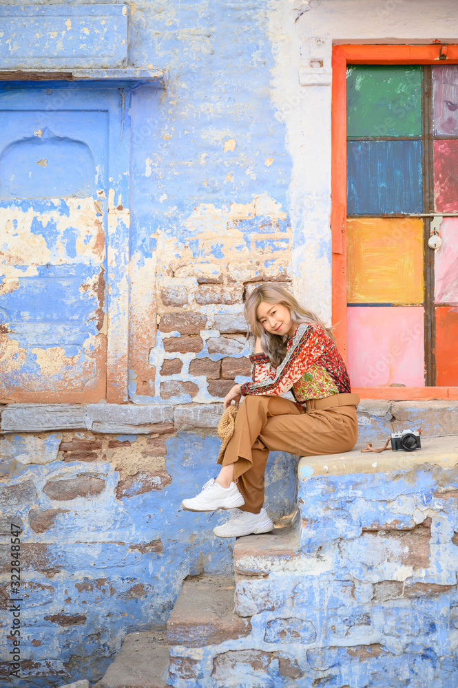 Portrait of young woman in front colorful blue tone building in Jodhpur the blue city in Rajasthan India
