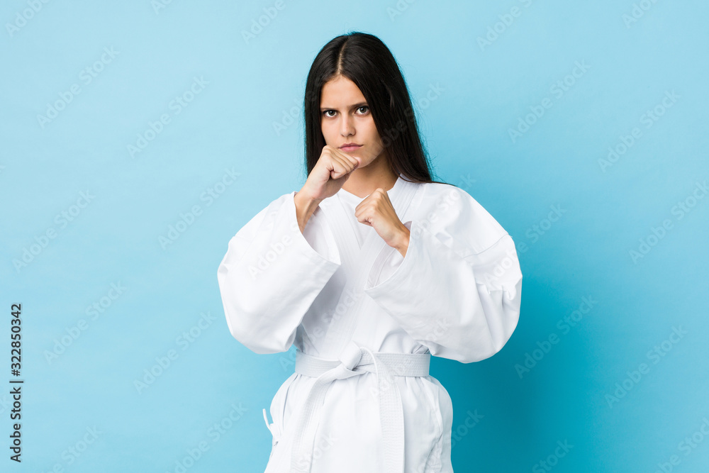 Young caucasian woman practicing karate isolated on a blue background Young caucasian woman practicing karate isolated on a blue background