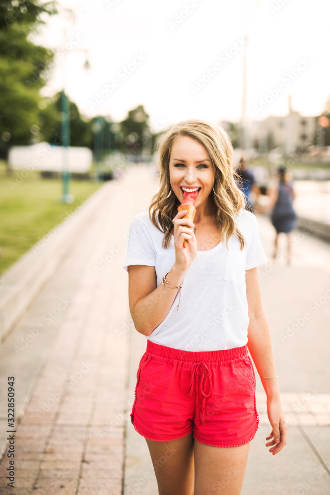 young woman licking an ice cream cone while walking in the summer evening young woman licking an ice cream cone while walking in the summer evening