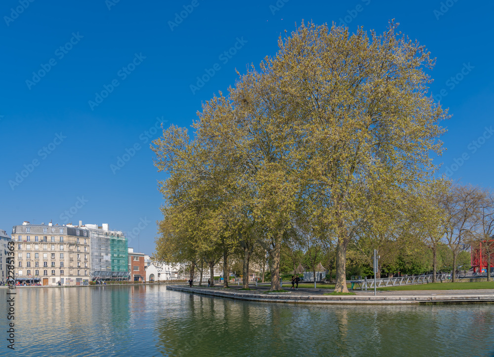 Paris, France - 04 14 2019: Ourcq Canal. Reflection of trees on water