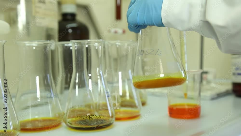 scientist pour orange liquid in Erlenmeyer Flask in laboratory scientist pour orange liquid in Erlenmeyer Flask in laboratory