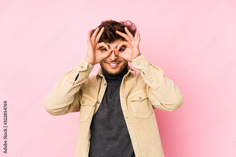 Young arabian man posing in a background isolated showing okay sign over eyes Young arabian man posing in a background isolated showing okay sign over eyes