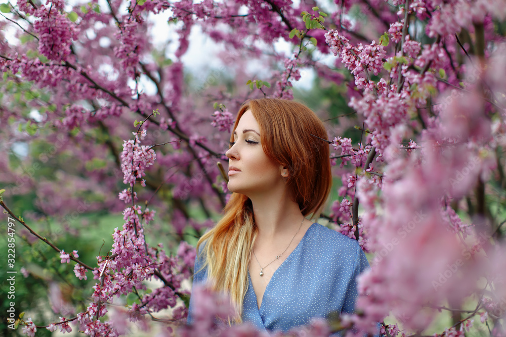 Beautiful dreaming redhead woman in spring time blossom cherrytrees garden. Beautiful dreaming redhead woman in spring time blossom cherrytrees garden.