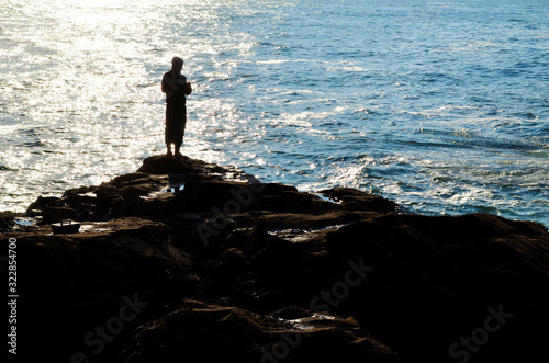 Man Standing on a Rocks above the Sea and Fishing