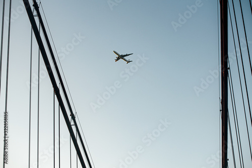 Suspension bridge under blue sky with flying plane