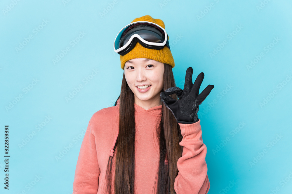 Young chinese woman wearing ski clothes isolated cheerful and confident showing ok gesture. Young chinese woman wearing ski clothes isolated cheerful and confident showing ok gesture.