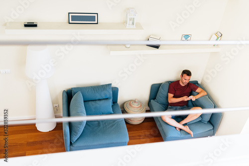Casual guy on armchair with smartphone