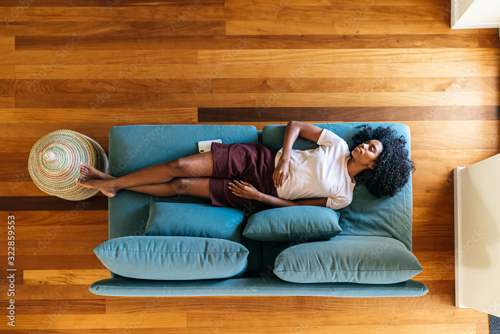 Young black lady sleeping on sofa at home - obrazy, fototapety, plakaty 