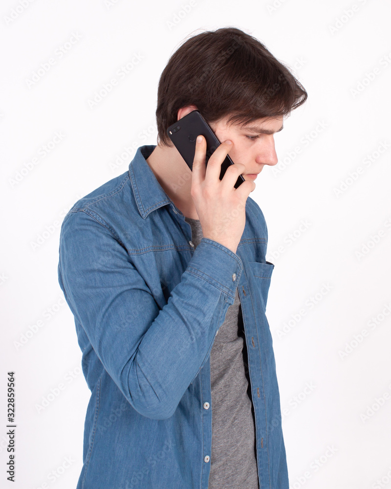 Young smiling man talking on the mobile phone and looking away. Isolated on white. Young smiling man talking on the mobile phone and looking away. Isolated on white.