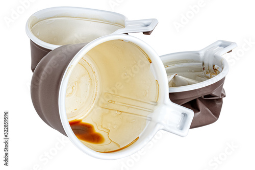 Used disposable white plastic mugs with brown satin texture on the outside with coffee stains and smudges isolated on white background