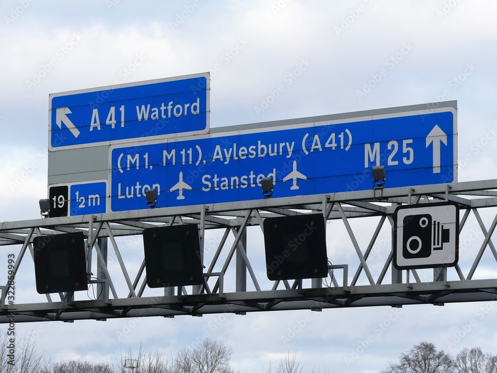 M25 Motorway signs and electronic displays on gantry, near Junction 19 in Hertfordshire, UK