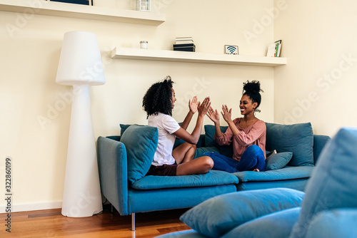 Pleased black females playing had clap game on sofa