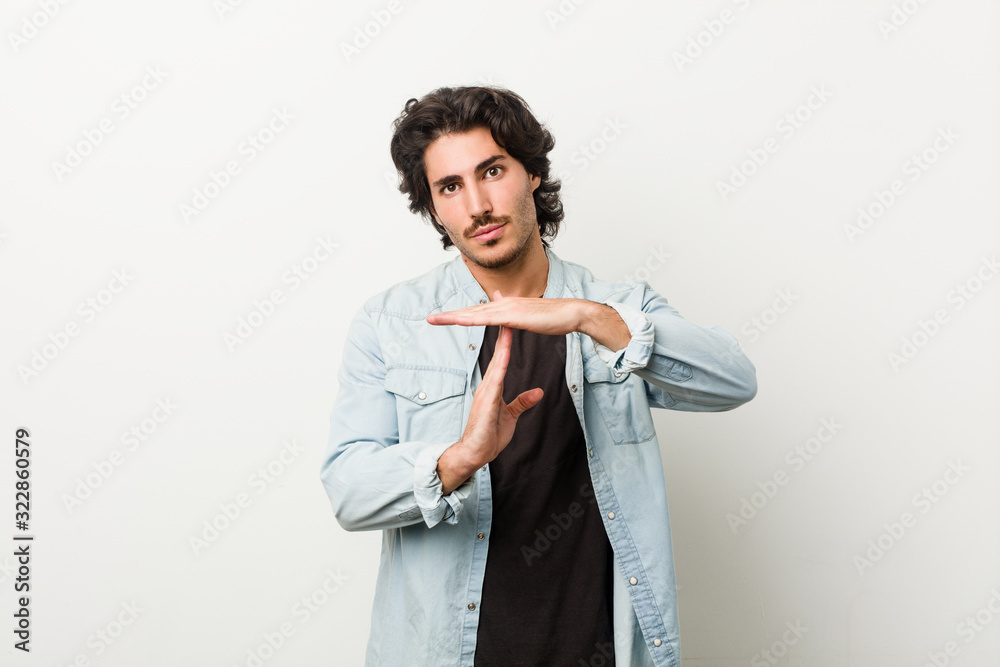 Young handsome man against a white background showing a timeout gesture. Young handsome man against a white background showing a timeout gesture.