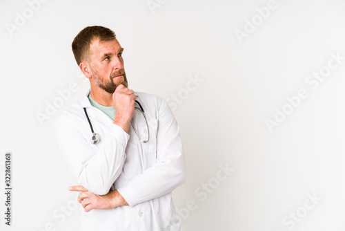 Senior doctor man isolated on white background looking sideways with doubtful and skeptical expression.