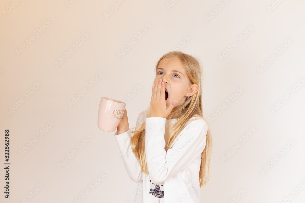 Blond girl yawning and with a cup of milk Blond girl yawning and with a cup of milk