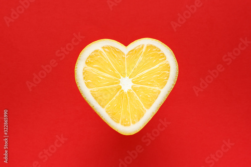 Yellow lemon in the shape of a heart on a red background.