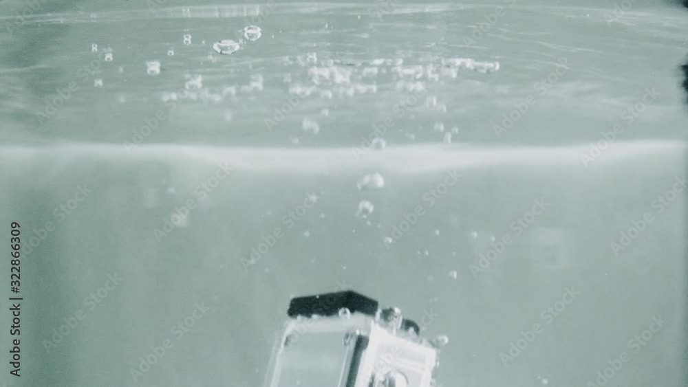 Waterproof action camera falling underwater close to the surface. Steady close camera shot.