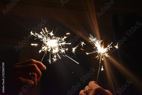 two sparklers in hands in the dark for a holiday