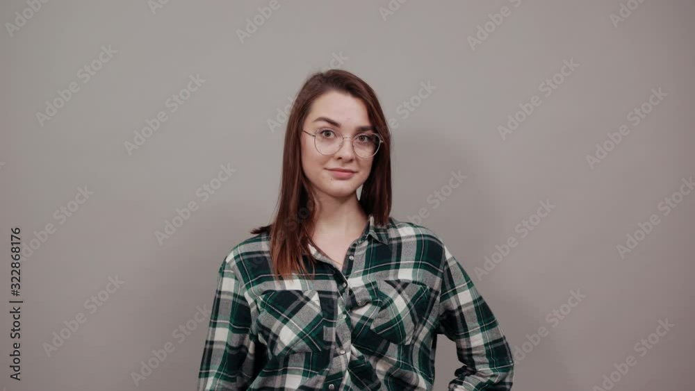 Young brunette girl blue green in checked shirt on grey background confident woman in glasses shows four fingers Young brunette girl blue green in checked shirt on grey background confident woman in glasses shows four fingers