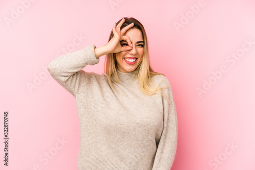 Middle age woman over isolated background excited keeping ok gesture on eye.