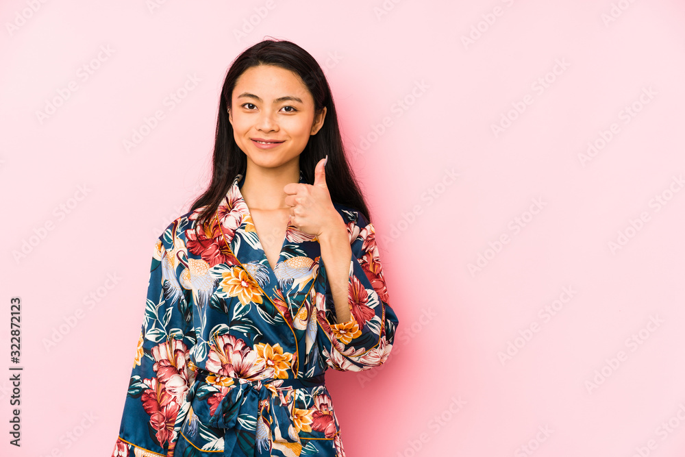 Young chinese woman wearing a asiatic pijama isolated smiling and raising thumb up Young chinese woman wearing a asiatic pijama isolated smiling and raising thumb up