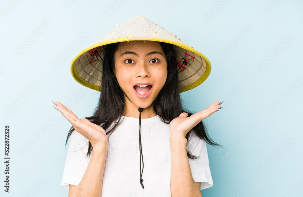 Young chinese woman wearing a vietnamese hay isolated screaming very angry and aggressive. Young chinese woman wearing a vietnamese hay isolated screaming very angry and aggressive.