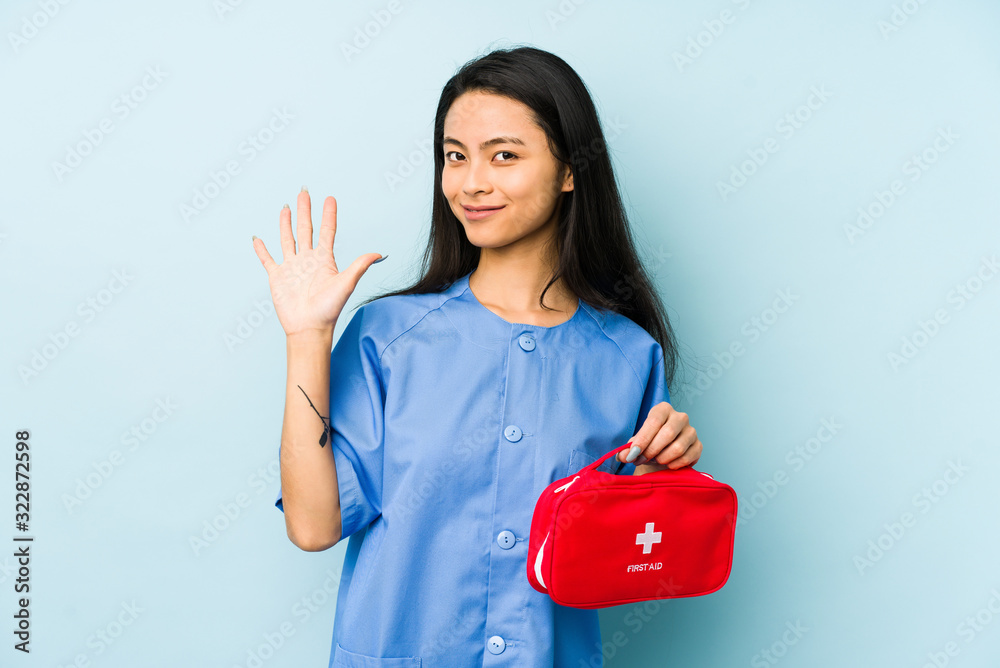Young chinese nurse woman isolated on a blue background showing a mobile phone call gesture with fingers.