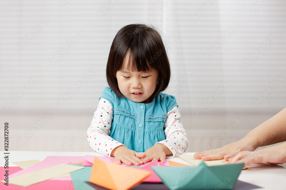 toddler girl learn making Origami at home against white background toddler girl learn making Origami at home against white background