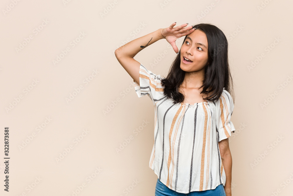 Young cute chinese teenager Young blonde woman wearing a coat against a pink background looking far away keeping hand on forehead. Young cute chinese teenager Young blonde woman wearing a coat against a pink background looking far away keeping hand on forehead.