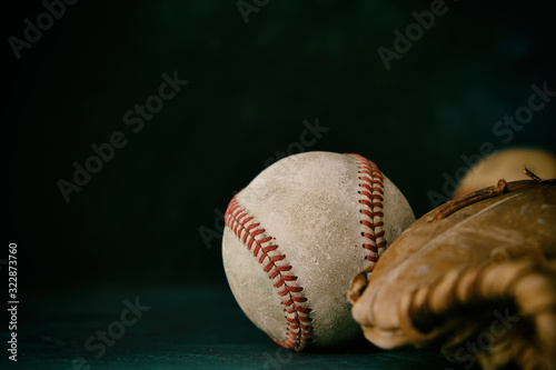 Old baseball ball with brown glove closeup, black background for sports text space.