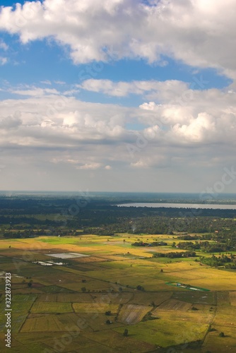 Green farmlands and crop fields on a sunny day near Siem Reap, Cambodia. Aerial view.