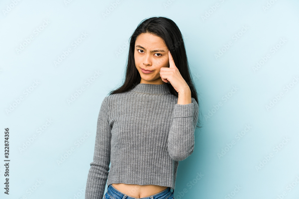 Young chinese woman isolated on a blue background pointing temple with finger, thinking, focused on a task.